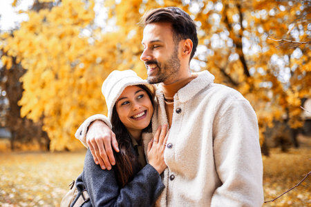 Romantic young couple embracing in colorful autumn park, love and happiness outdoors in fall season.の写真素材