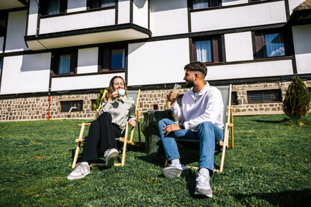 Young couple enjoying coffee on loungers in the sunの写真素材