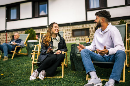 Happy young couple enjoying coffee and juice on loungers in front of hotel during autumn, peaceful and romantic fall getaway.の写真素材