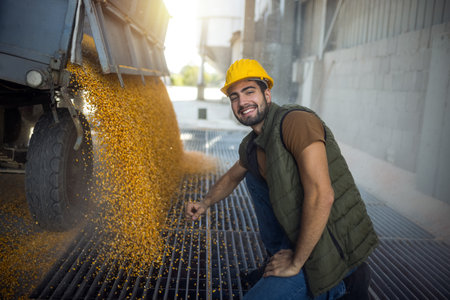 Truck unloading corn at collection point with workerの写真素材