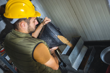 Young agricultural worker inspecting and collecting wheat samples before storage at grain facility, ensuring quality and proper handling.の写真素材