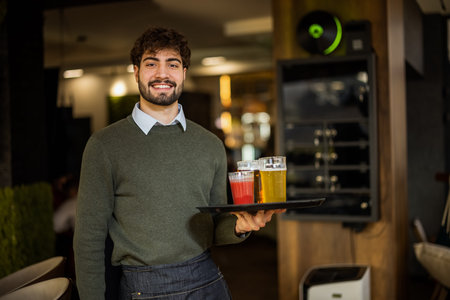 Portrait of smiling waiter holding tray with drinks in a coffee shop