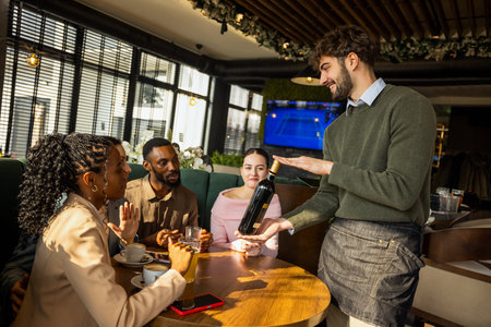 Professional waiter suggesting a bottle of wine to a group of friends in a cafe, creating a friendly...
