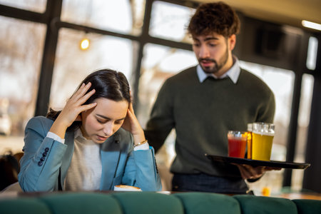 Friendly waiter comforting a young woman in a restaurant, showing empathy, care, and attentive service in a warm, supportive environment.の写真素材