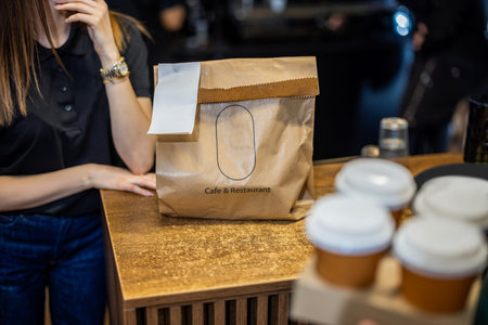 Woman talking on the phone and holding a paper bag in the cafe