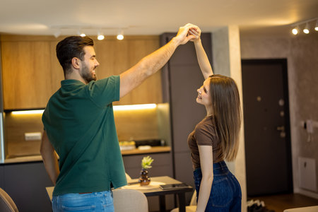 Young couple dancing together in the living room at home. People having fun and dancing.の写真素材