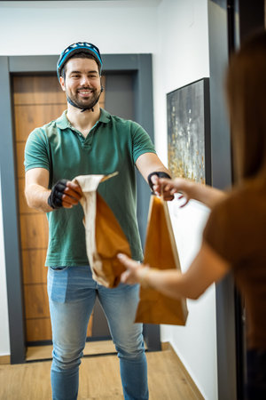 Smiling delivery man delivering parcel to customer at door in the house