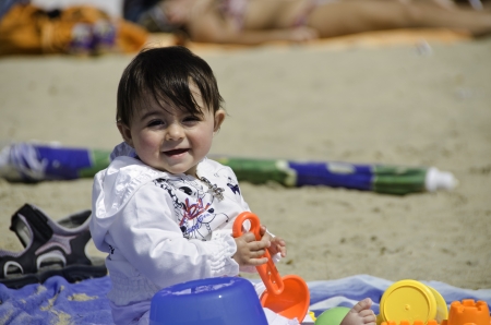 Baby Girl relaxing and playing on a Beach Towel, Italyの写真素材