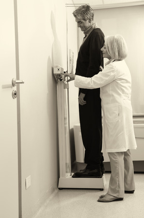 Man standing on weight machine with female doctor analyzing results.の写真素材