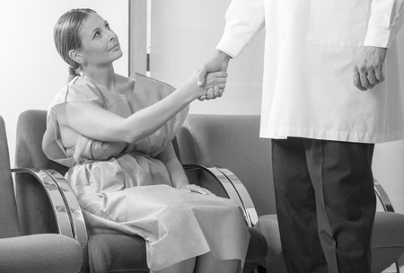 Woman patient in 40s shaking hand with doctor in hospital waiting room before checkup.の写真素材