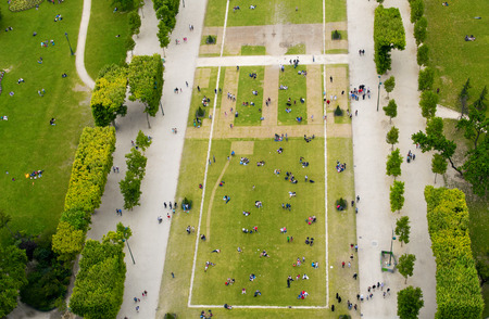 Crowd of tourists relaxing in Champs de Mars gardens, under the Eiffel Tower, Paris - France.の写真素材