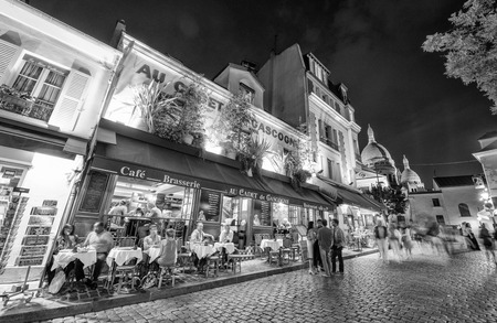 PARIS - JUNE 23, 2014: Tourists and locals walk in Montmartre streets at night. Montmartre attracted many famous modern painters in the early 20th centuryのeditorial素材