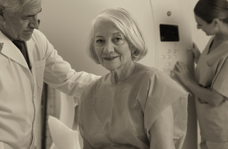 Senior male doctor and female assistant examining woman in 70s with CT scanner. Computerised tomography.の写真素材