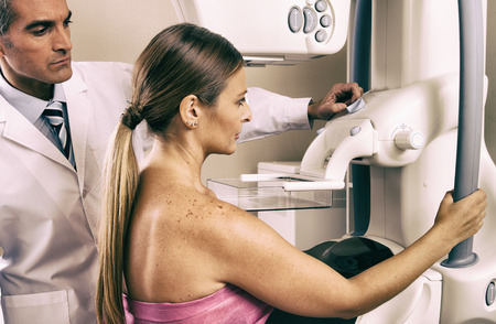 Male doctor checking mammography machine scan with patient woman in 40s.の写真素材