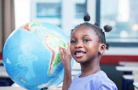 Young afro american black girl at school smiling touching a world globe.の写真素材