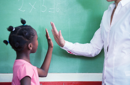 Teacher congratulating with afro american female student in mathematics lesson.の写真素材