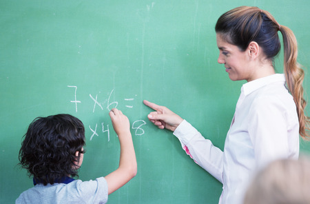 Teacher questioning kid at chalkboard.の写真素材