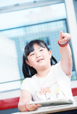 Asian girl at school pointing with her finger.の写真素材