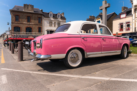 CANCALE, FRANCE - JUNE 23, 2014: Pink vintage car on the coastal road. These cars are used mostly for advertising and are very common in Brittany.のeditorial素材