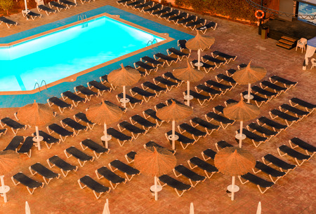 Raws of sunbeds in front of pool in a resort, night view. Vacation and holidays concept.のeditorial素材