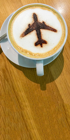 Cup of Coffee with airplane sign on foam. Copyspace.