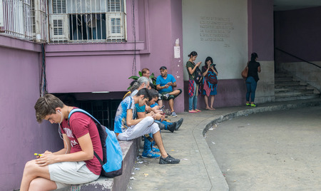 HAVANA, CUBA - APRIL 5, 2016: Young people on a city square using smartphones. This is the beginning of a new era for Cuba.のeditorial素材
