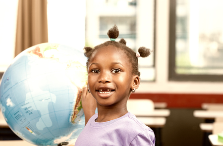 Afro american girl at elementary school with earth globe learning geography.の写真素材