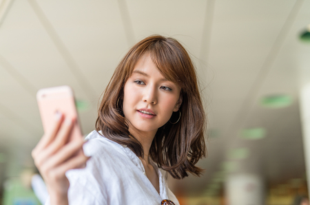 Young asian girl making selfie with smartphone inside subway.の写真素材