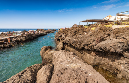 GARACHICO, SPAIN - SEPTEMBER 3, 2016: People enjoy city pools. They are natural pools made with volcanic debris of northern coastline of Tenerife.のeditorial素材