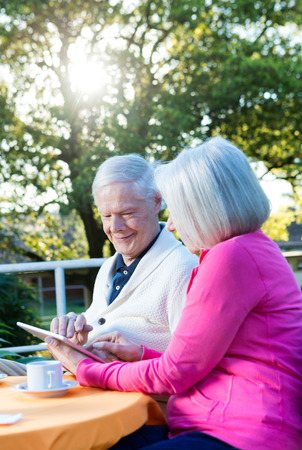 Happy elder couple in 70s outdoor with technology gadget.の写真素材