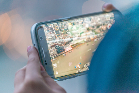 Woman making picture to city night skyline with mobile phone.