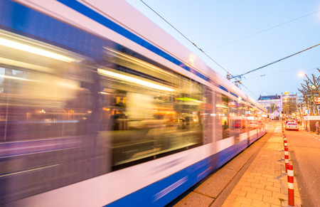 Amsterdam. Tram speeding at sunset in city streets.