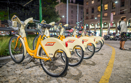 MILAN - SEPTEMBER 25, 2015: Bike Mi bicycles parked at night. They are rental with stations across the whole city.のeditorial素材