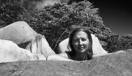 Beautiful woman leaning on a rock in Seychelles.の写真素材