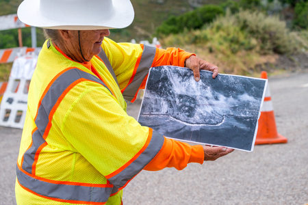 BIG SUR, CA - AUGUST 3, 2017: Woman shows winter landslide damage in Cabrillo Highway. The road is still under construction.のeditorial素材