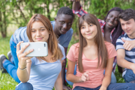 Multi ethnic group of teenagers happy making selfie on the grass.の写真素材