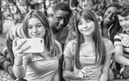 Group of multi ethnic teenagers making selfie seated on the grass.の写真素材