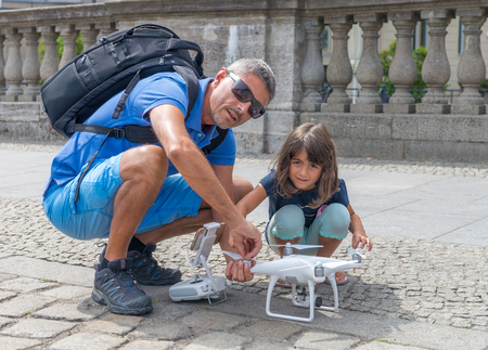 Man in 40s showing his daughter how to setup his drone for flying.
