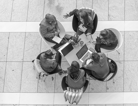 Group of workers discussing at a table with laptops, downward view.の写真素材