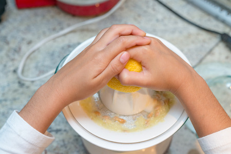 Little girl hands squeezing lemon with machine.の写真素材