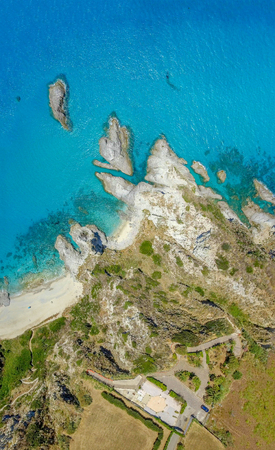 Downward view of Italian coastline with rocks and trees.