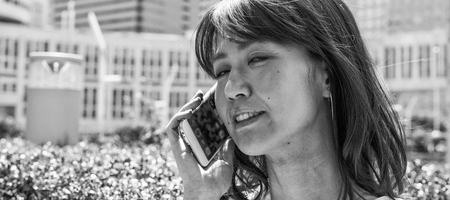 Happy asian girl talking at smartphone and smiling along city streets.の写真素材