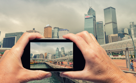 Man and woman hand capturing Hong Kong skyline with smartphone.の写真素材