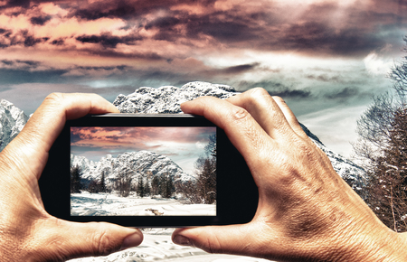 Man and woman hand capturing Alpin Winter landscape with smartphone