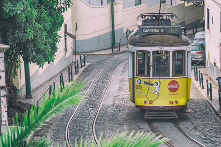 LISBON - NOVEMBER 1, 2018: Yellow tram speeds up along city street. Lisbon attracts 3 million tourists annually.のeditorial素材