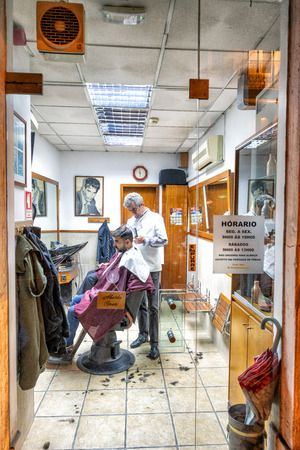 LISBON - OCTOBER 31, 2018: Barber shop with man cutting hairs. Some shops are open even at night.のeditorial素材