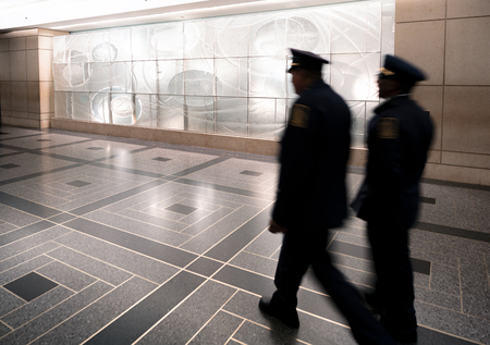 Police officers walking inside main station, blurred view