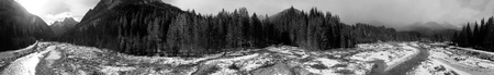 Aerial panoramic view of mountain valley in winter with snow, forest and river.