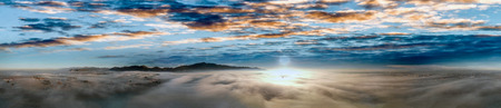 Panoramic aerial view of countryside scenario surrounded by fog, view from drone above the clouds at...