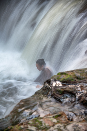 ROTORUA, NEW ZEALAND - SEPTEMBER 1, 2018: Woman enjoys hot waters of Kerosene Creek Falls. This is a free pool in Rotorua area.のeditorial素材